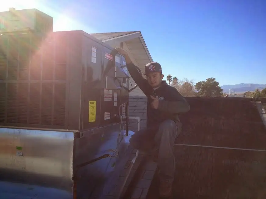 HVAC technician performing AC Tune-Up on a rooftop unit in West Bloomfield